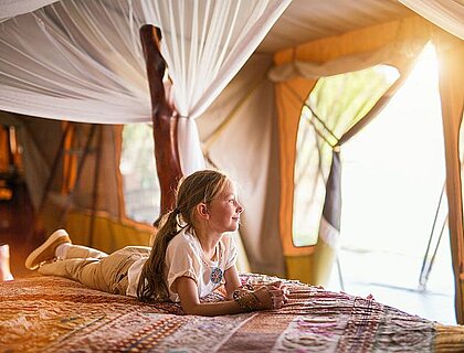 Little girl in safari tent enjoying luxury vacation in Africa