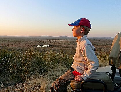Easter family safari holidays - Picture of a boy sitting on the tracker's seat of a safari vehicle,enjoying the view, South Africa.