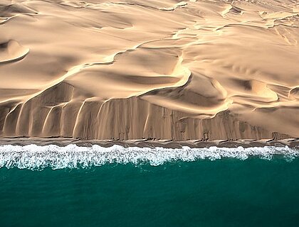 Skeleton Coast Safaris - fly-in destination, Aerial view of Skeleton coast sand dunes meeting the waves of Atlanic ocean. Skeleton coast, Namibia.
