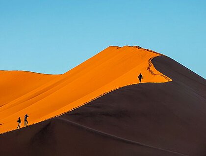 Sossusvlei Namibia - Silhouettes of people climbing Big Daddy sand dune at sunrise in Sossusvlei, Namibia